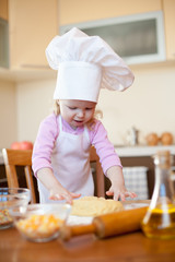 Little girl on kitchen kneads dough