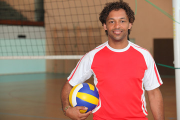 Volleyball player stood with ball under arm