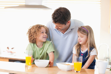 Obraz na płótnie Canvas Smiling father with his children having breakfast