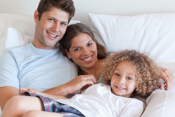 Fototapeta premium Smiling family relaxing on a bed