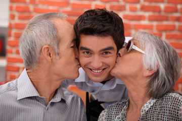 Grandparents kissing their adult grandson