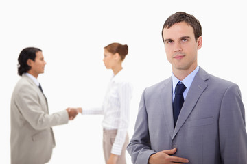 Businessman with hand shaking colleagues behind him
