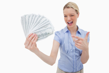 Woman holding money and pointing at it