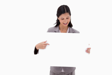 Fototapeta premium Businesswoman looking and pointing at blank sign board