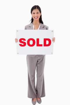Smiling real estate agent with sold sign