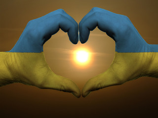 Heart and love gesture by hands colored in ukraine flag during b - obrazy, fototapety, plakaty