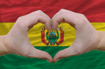 Heart and love gesture showed by hands over flag of bolivia back