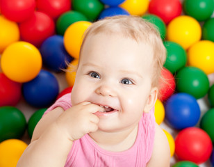 Portrait of a smiling infant sitting among colorful balls