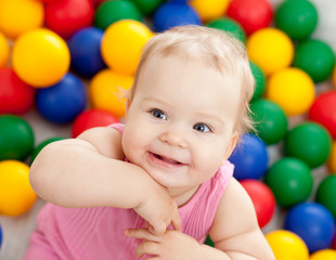 Portrait of a smiling infant playing among colorful balls