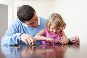 Fototapeta premium Dad and daughter puts coins