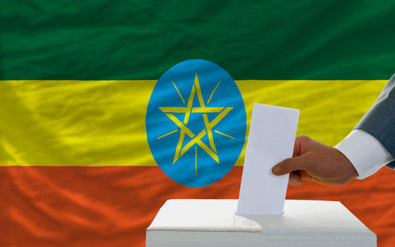 man voting on elections in ethiopia in front of flag