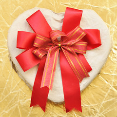 Heart-shaped box with bow on a gold background