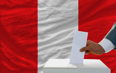 man voting on elections in peru in front of flag