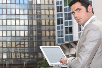 Man using his laptop outside an office block