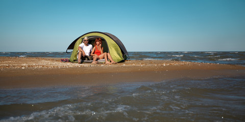 Obraz premium happy young couple sitting in tent seaside