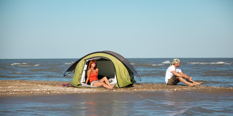 happy young couple sitting in tent seaside
