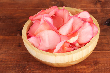 beautiful pink rose petals in wooden bowl on table