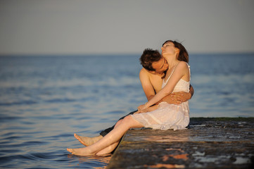 Fototapeta na wymiar Younf man kissing his girlfriend on a pier