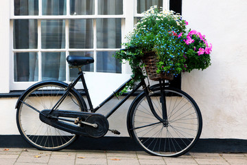 Fototapeta na wymiar Old advertising bicycle with basket of flowers