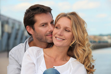 Man kissing his partner by the water