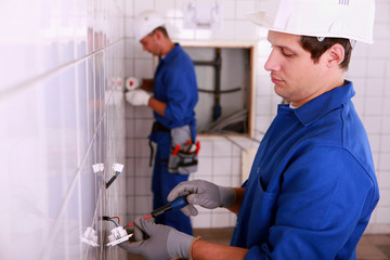 Electricians plumbing a bathroom