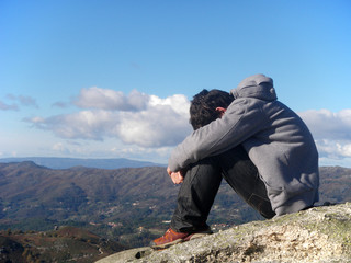 young man sitting on the top of a mountain