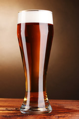 beer in glass on wooden table on brown background