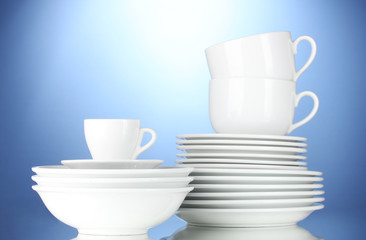 empty bowls, plates and cups on blue background