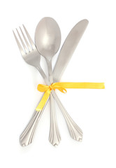 Silver fork and spoon, knife tied with a yellow ribbon isolated