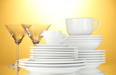 empty bowls, plates, cups and glasses on yellow background