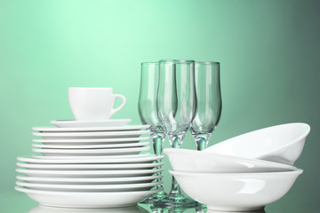 Fototapeta premium Clean plates, cup and glasses on green background