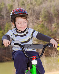 Obraz premium Boy riding bike with safety helmet outdoors at park