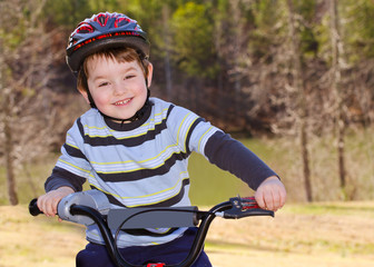 Fototapeta na wymiar Boy riding bike with safety helmet outdoors at park