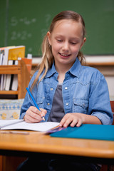 Portrait of a happy schoolgirl writing