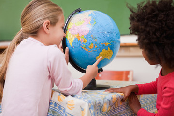 Little schoolgirls looking at a globe