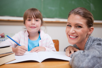Fototapeta na wymiar Schoolgirl writing with her teacher