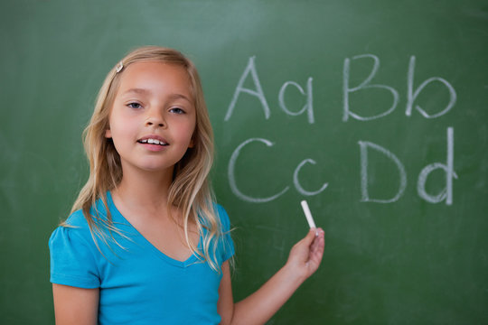 Smiling schoolgirl showing letters