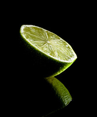 Bright green natural lime on black mirror background