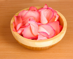 beautiful pink rose petals in wooden bowl on table