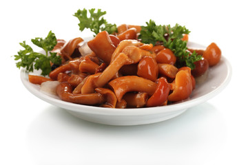 Marinated mushrooms in white saucer isolated on white