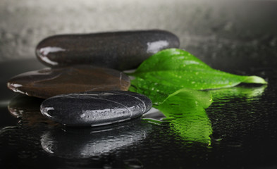spa stones with water drops and leaves on black background
