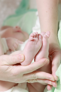 Newborn baby feet in mother's hands with soft yellow blanket