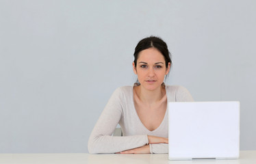 Jeune femme avec ordinateur portable sur fond gris