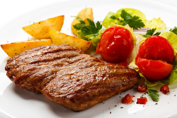 Grilled steak, baked potatoes and vegetable salad