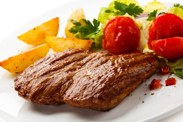 Grilled steak, baked potatoes and vegetable salad
