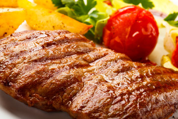 Grilled steak, baked potatoes and vegetable salad