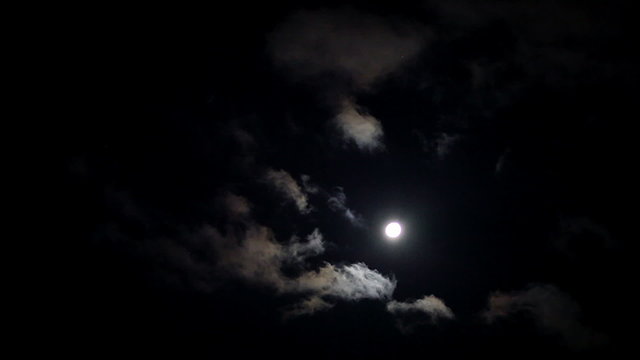 Moonlit night with fleecy clouds passes on dark blue sky