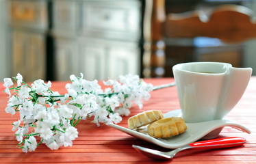 Cup of coffee with cookies and white flowers
