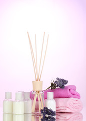 Obraz na płótnie Canvas Bottle of air freshener, lavander and towels on pink background
