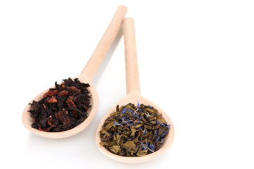 Dry green and black tea in wooden spoons isolated on white